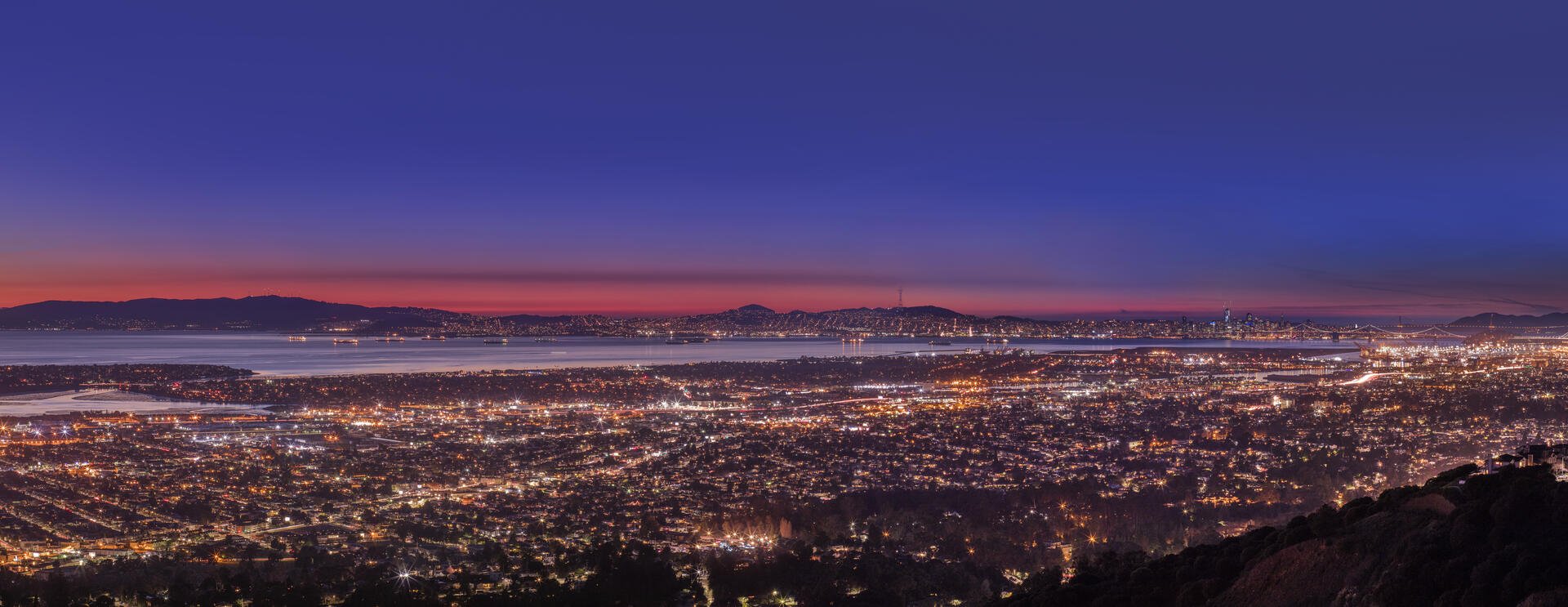 East Bay panorama at dusk from the hills — San Leandro, Oakland and San Francisco skyline with Bay Bridge